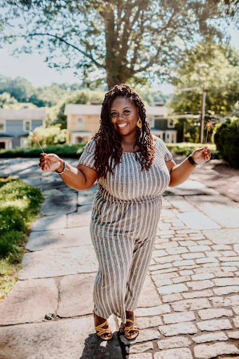 photo of Educational Leadership graduate student Garria Yuille outside smiling and holing sparklers in sunshine. 