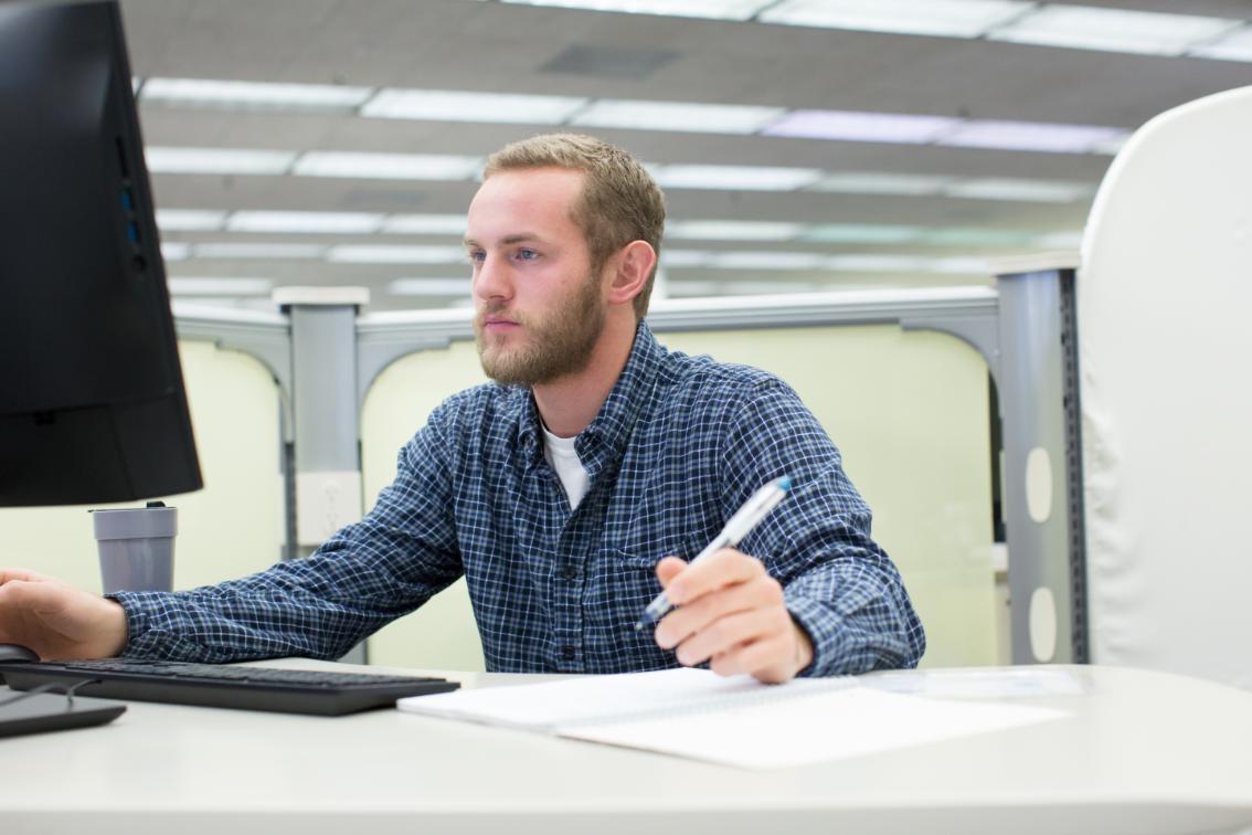 Student sits working on desktop computer