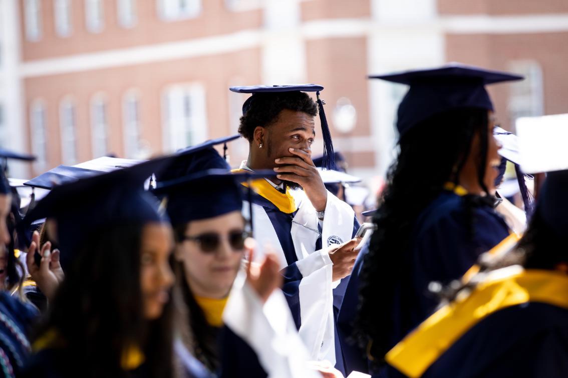 Student holding their hand over their mouth during a moment at Commencement